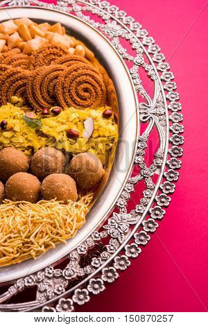 Plate full of indian festival food or diwali food or snacks like laddu, chivda, chakali or murukku, sev and shankar pale, sweet and salty snack food