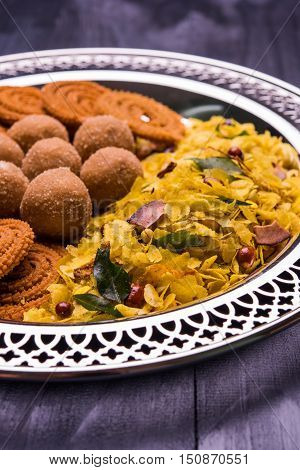 Plate full of indian festival food or diwali food or snacks like laddu, chivda, chakali or murukku, sev and shankar pale, sweet and salty snack food