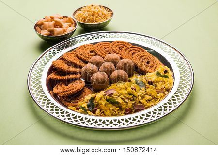 Plate full of indian festival food or diwali food or snacks like laddu, chivda, chakali or murukku, sev and shankar pale, sweet and salty snack food