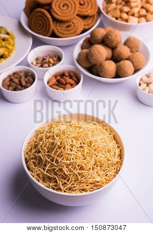 home made tasty Diwali food or Diwali snacks or Diwali sweets like rava laddu, chakli, sev,shankar pale and chivda or chiwada with dry fruits in white bowls, favourite indian diwali recipe
