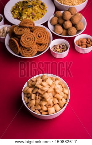 homemade tasty Diwali food or Diwali snacks or Diwali sweets like rava laddu, chakli, sev, shankar pale and chivda or chiwada with dry fruits in white bowls, favourite indian diwali recipe