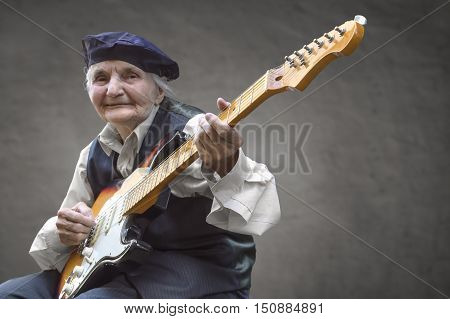 Elderly woman playing a guitar. Selective focus.