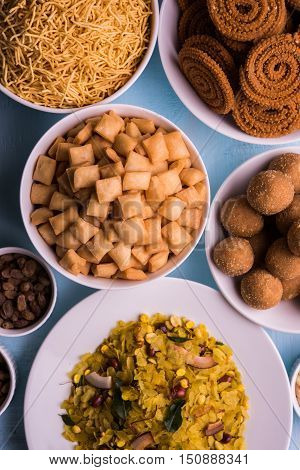 homemade tasty Diwali food or Diwali snacks or Diwali sweets like rava laddu, chakli, sev, shankar pale and chivda or chiwada with dry fruits in white bowls, favourite indian diwali recipe