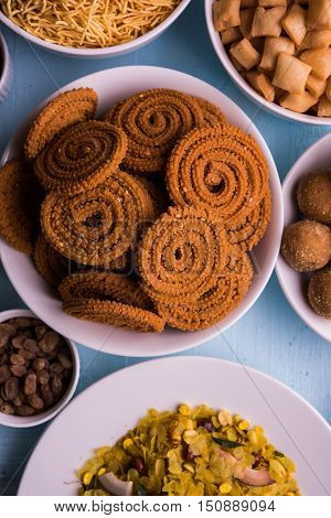 homemade tasty Diwali food or Diwali snacks or Diwali sweets like rava laddu, chakli, sev, shankar pale and chivda or chiwada with dry fruits in white bowls, favourite indian diwali recipe