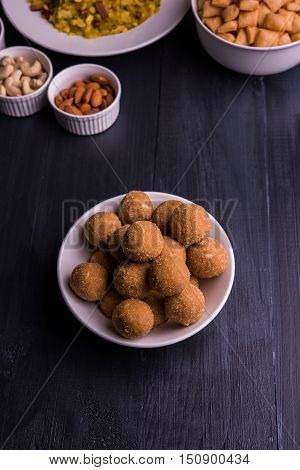 homemade tasty Diwali food or Diwali snacks or Diwali sweets like rava laddu, chakli, sev, shankar pale and chivda or chiwada with dry fruits in white bowls, favourite indian diwali recipe