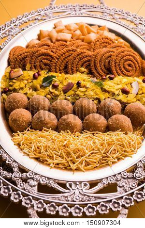 Plate full of indian festival food or diwali food or snacks like laddu, chivda, chakali or murukku, sev and shankar pale, sweet and salty snack food