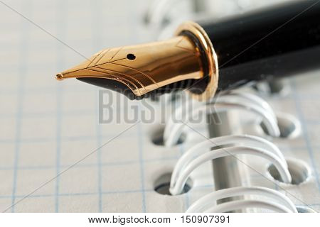 Gold fountain pen close-up on notebook sheet. Photo closeup Pen