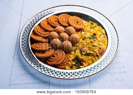 Plate full of indian festival food or diwali food or snacks like laddu, chivda, chakali or murukku, sev and shankar pale, sweet and salty snack food