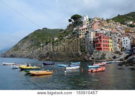 Riomaggiore Italy - September 4 2016: Buildings and boats in Riomaggiore city in Liguria Italy. One of five Cinque Terre cities (unesco world heritage). Unidentified people visible.