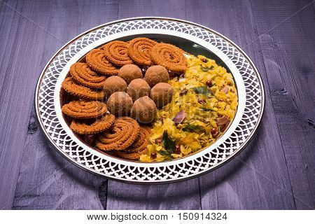 Plate full of indian festival food or diwali food or snacks like laddu, chivda, chakali or murukku, sev and shankar pale, sweet and salty snack food