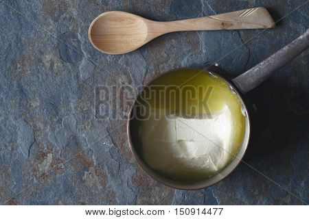 Melted butter in the stewpan on the stone background top view