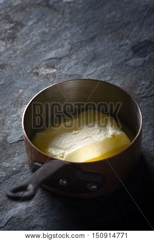 Melted butter in the stewpan on the stone background