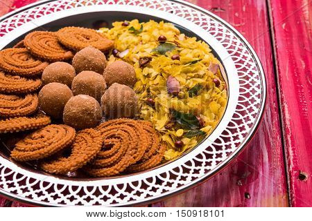 Plate full of indian festival food or diwali food or snacks like laddu, chivda, chakali or murukku, sev and shankar pale, sweet and salty snack food