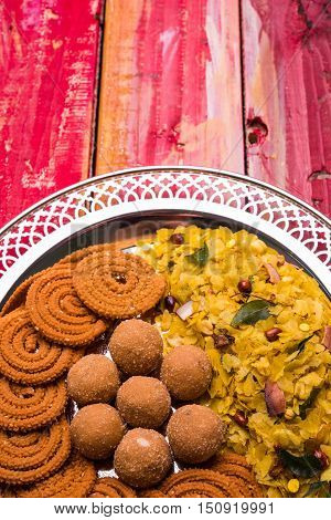 Plate full of indian festival food or diwali food or snacks like laddu, chivda, chakali or murukku, sev and shankar pale, sweet and salty snack food