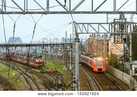 SAINT-PETERSBURG RUSSIA - September 27 2016: modern locomotive pulling a high-speed electric train Lastochka on rails. Technical railway station - operational locomotive depot. Workers in overalls serve rail journey. Transport infrastructure of Russian Ra