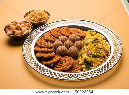 Plate full of indian festival food or diwali food or snacks like laddu, chivda, chakali or murukku, sev and shankar pale, sweet and salty snack food