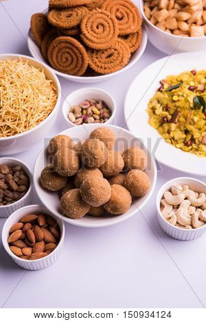home made tasty Diwali food or Diwali snacks or Diwali sweets like rava laddu, chakli, sev,shankar pale and chivda or chiwada with dry fruits in white bowls, favourite indian diwali recipe