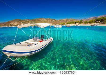 Motor boat with mountains pine trees and sandy beach in the background near Sagone Corsica France Europe.