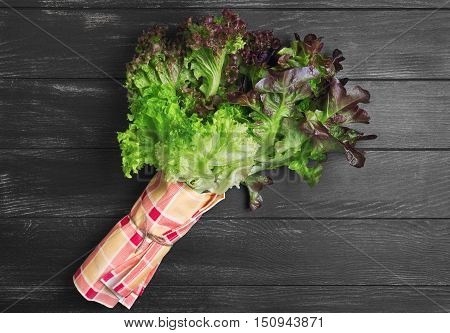 Bundle of fresh leaves of green and red lettuce. Napkin cloth. Varieties of leaves lettuce salad Roxay Lugano Satin. Dark black wooden background. Top view.
