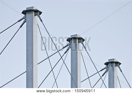 Tied Suspension Roof Cables Three Tall Grey Masts Cable-suspended Swooping Rooftop Pylon Anchors Pale Blue Summer Sky Large Detailed Horizontal Closeup Contemporary Construction Concept