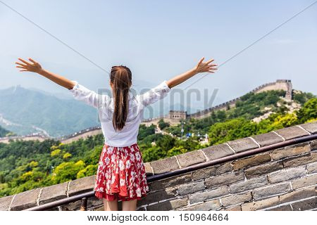 Happy cheerful tourist woman at Great Wall of China having fun un arms outstretched on travel during vacation trip in Asia. Girl visiting and sightseeing Chinese destination in Badaling
