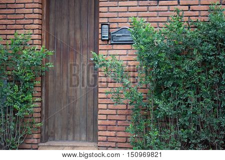 Wooden door entry with mailbox and intercom on a brick wall