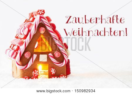 Gingerbread House In Snowy Scenery As Christmas Decoration With White Background. Candlelight For Romantic Atmosphere. German Text Zauberhafte Weihnachten Means Magic Christmas