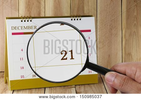 Magnifying glass in hand on calendar you can look Twenty-one date of monthFocus number Twenty-one in DecemberConcept in business and meetings.