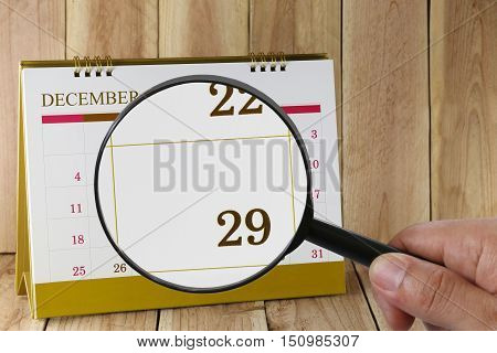 Magnifying glass in hand on calendar you can look Twenty-nine date of monthFocus number Twenty-nine in DecemberConcept in business and meetings.
