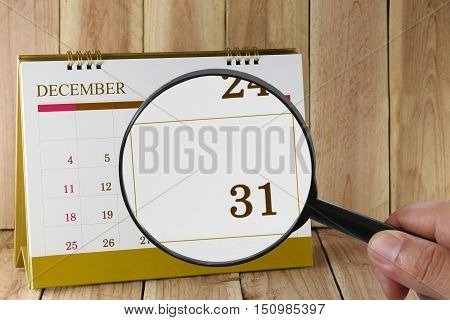 Magnifying glass in hand on calendar you can look thirty-one date of monthFocus number thirty one in DecemberConcept in business and meetings.