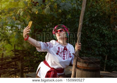 girl in national costume and wearing glasses makes selfie