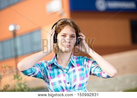 Young beautiful girl listening to music player on the street. tudent woman at campus park.