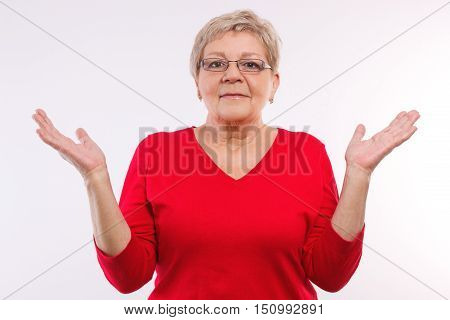 Happy smiling elderly senior woman throwing up her hands and shrugging shoulders human emotions and gesture having no clue