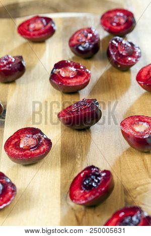 Red Juicy Cherries, Cut Into Halves And Lying On A Wooden Board, Close-up Photo