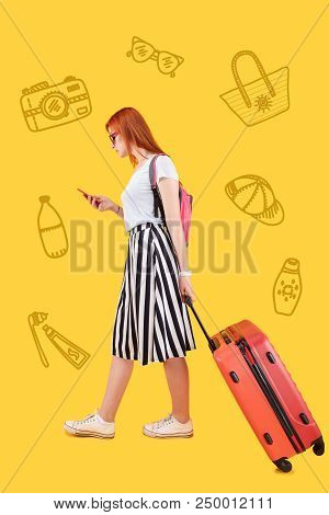 Busy Traveler. Calm Attentive Traveler Carrying A Pink Suitcase And Looking At The Screen Of Her Sma