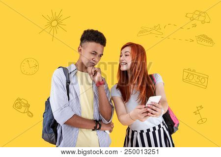 Please Look. Calm Student Touching His Chin And His Girlfriend Feeling Excited While Showing Him Her