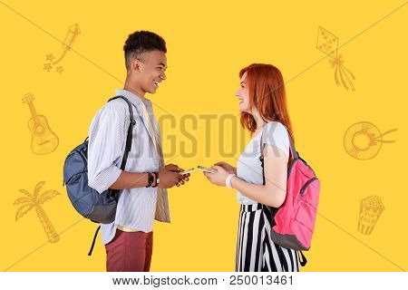Finding Common Ground. Cheerful Easy Going Students Standing Opposite Each Other With Smartphones In