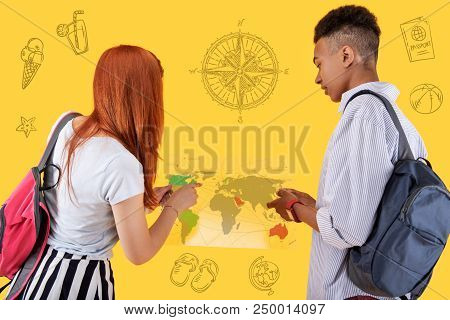 Transparent Map. Two Friends Wearing Backpacks And Looking Attentively At The Map Of The World In Th