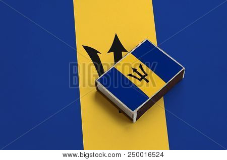 Barbados Flag  Is Pictured On A Matchbox That Lies On A Large Flag.