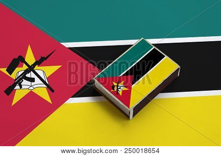 Mozambique Flag  Is Pictured On A Matchbox That Lies On A Large Flag.