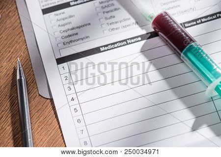 Selective Focus Of Medical Questionary And Syringe With Blood Sample On Table, World Hepatitis Day C