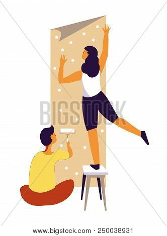 Husband And Wife Make Repairs And Change Wallpaper. Woman Places Stripe Of Paper On Wall Standing On