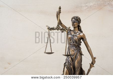 The Statue Of Justice Themis Or Iustitia, The Blindfolded Goddess Of Justice Against Marble Wall Bac