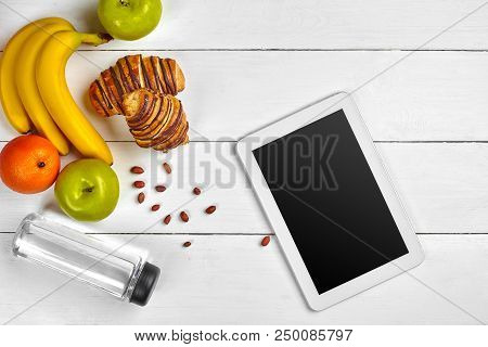 Healthy Breakfast Of Fresh Fruits And Croissant On Wooden Table With Tablet. Empty Screen. Top View.