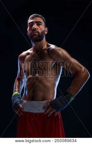 Handsome Athletic Guy In A Red Shorts On A Black Background. The Boxer Is Fetching His Breath After 