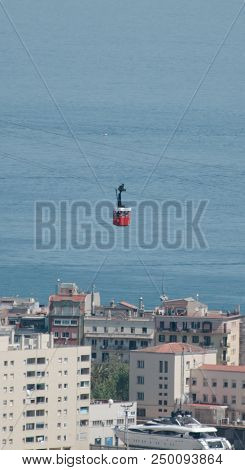 Red Funicular Rides Over The City On The Sea Background