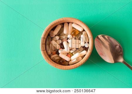 Lots Of Colorful Pills In A Plate With Spoon On Turquoise Background . The Concept Of A Healthy Life
