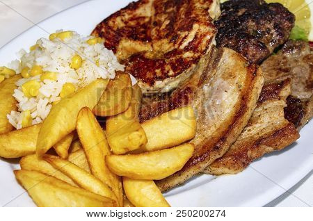 Grilled Pork And Goat Meat Dish With French Fries And Rice With Corn And Lime With Cucumber