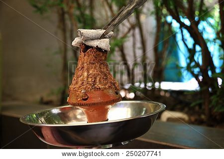 A Coal Being Placed Over Ajami Tobacco Leaves In A Hookah Head.