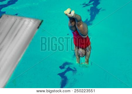 Female Diver Jumping Into The Pool From Diving Board